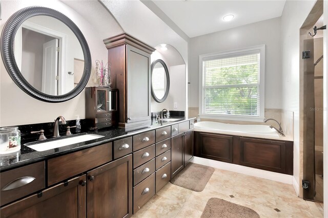 bathroom with double vanity, a washtub, and tile patterned floors