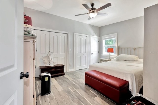 bedroom featuring ceiling fan, light wood-type flooring, and two closets