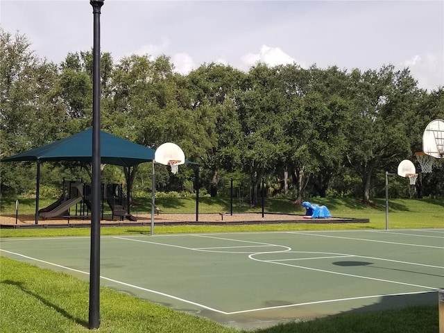 view of basketball court with a playground and a lawn