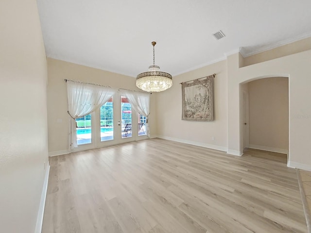 spare room featuring light wood-type flooring, an inviting chandelier, and ornamental molding