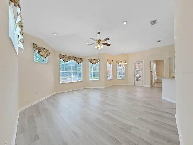 spare room featuring light wood-type flooring, lofted ceiling, and ceiling fan with notable chandelier