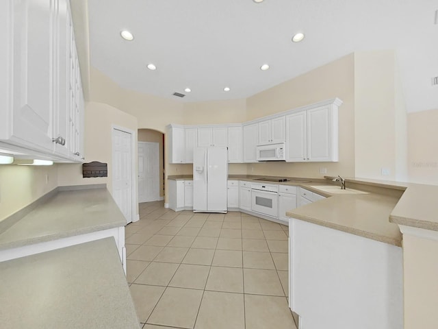 kitchen with white appliances, light tile patterned floors, sink, kitchen peninsula, and white cabinets