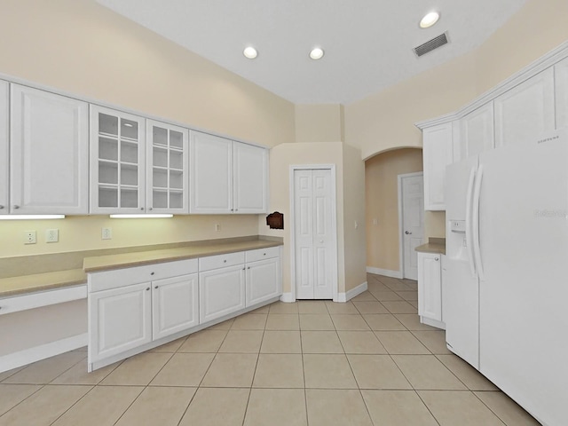 kitchen with white fridge with ice dispenser, white cabinets, and light tile patterned floors