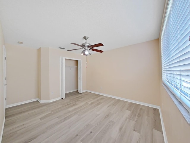 empty room with ceiling fan and light hardwood / wood-style flooring