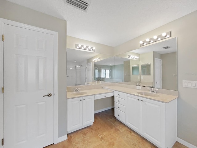 bathroom featuring an enclosed shower, vanity, and a textured ceiling