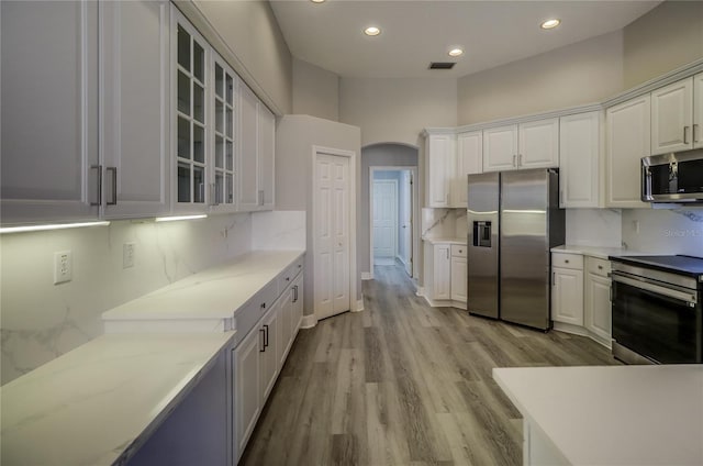 19334 Autumn Woods Ave, Tampa, FL 33647 - kitchen with visible vents, decorative backsplash, glass insert cabinets, white cabinets, and appliances with stainless steel finishes