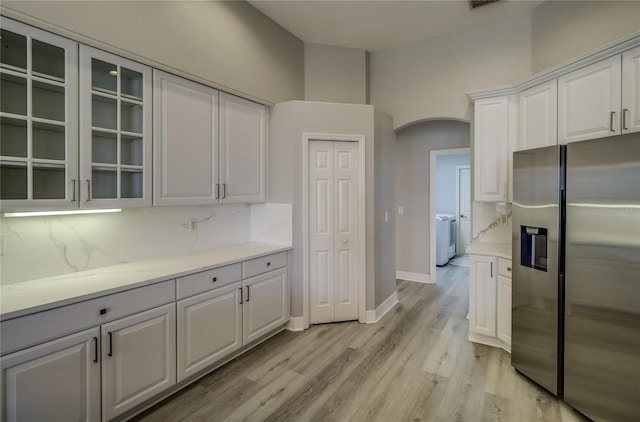 19334 Autumn Woods Ave, Tampa, FL 33647 - kitchen with independent washer and dryer, arched walkways, tasteful backsplash, stainless steel fridge with ice dispenser, and light wood-style flooring