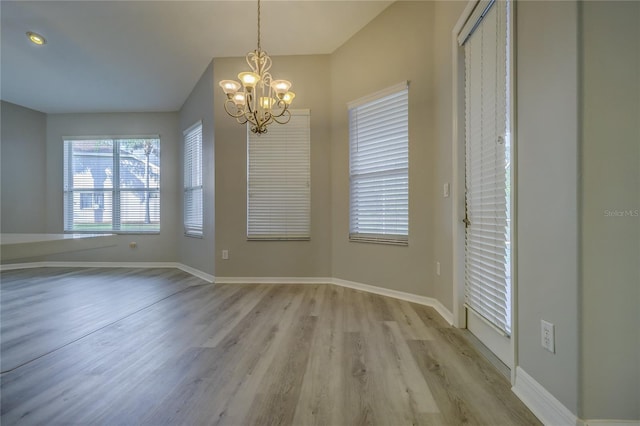 19334 Autumn Woods Ave, Tampa, FL 33647 - unfurnished dining area featuring baseboards, a notable chandelier, and light wood-style flooring