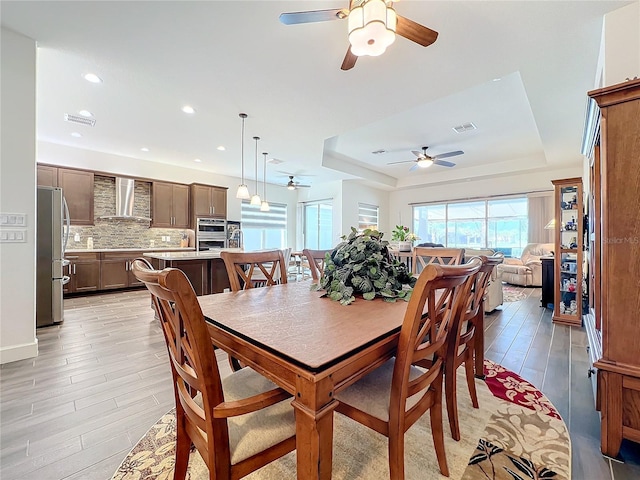 dining space featuring light hardwood / wood-style floors and a raised ceiling