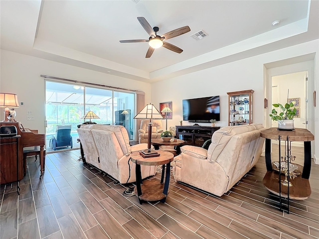 living room with ceiling fan and a tray ceiling