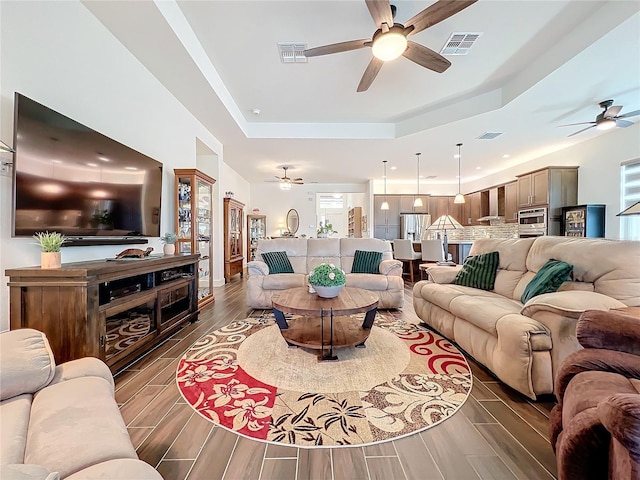 living room with ceiling fan and a tray ceiling