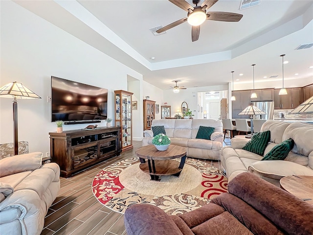 living room featuring ceiling fan and a raised ceiling