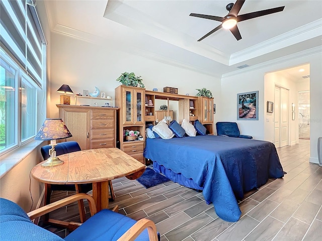 bedroom with ornamental molding, ceiling fan, and a tray ceiling