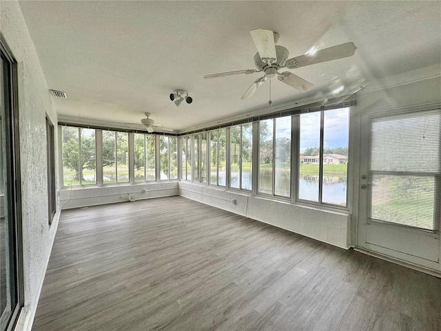 unfurnished sunroom featuring a water view and ceiling fan