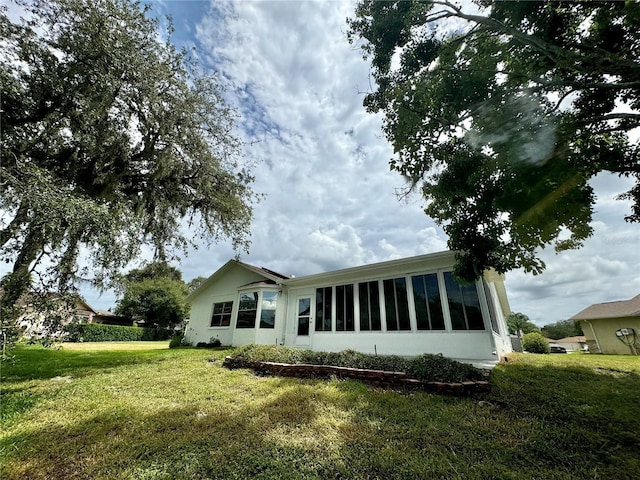 back of property with a yard and a sunroom