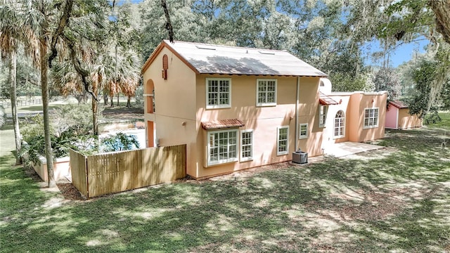 back of property with central air condition unit and a lawn