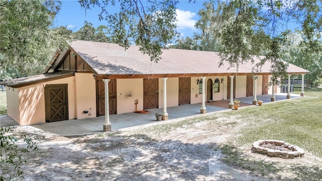 view of front of house with a fire pit, a patio, and a front lawn