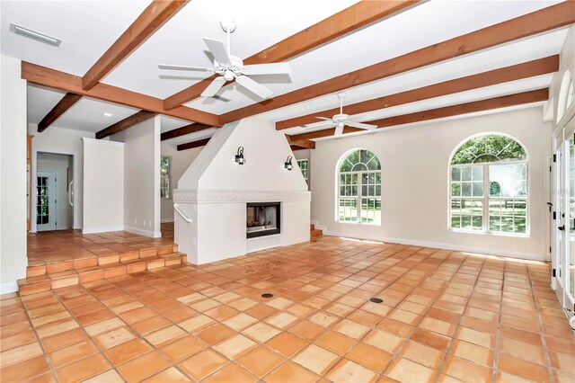 unfurnished living room with ceiling fan, a fireplace, beam ceiling, and light tile patterned floors