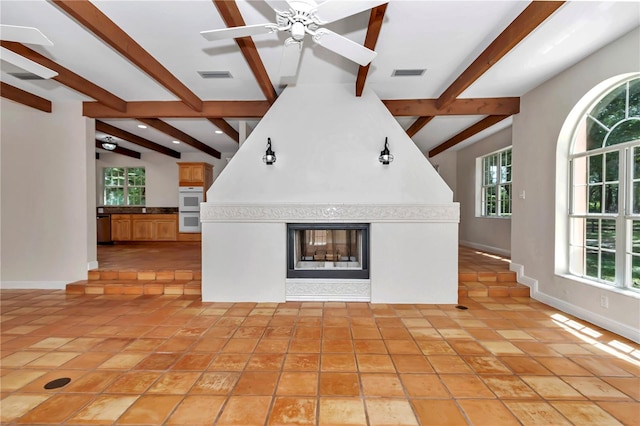 interior space featuring plenty of natural light, beamed ceiling, ceiling fan, and light tile patterned floors