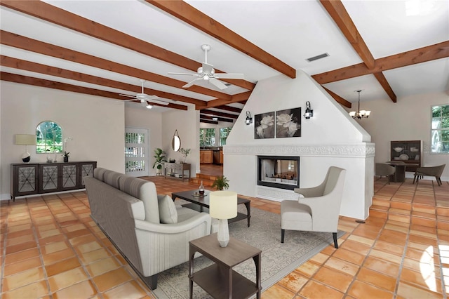 tiled living room featuring lofted ceiling with beams, a multi sided fireplace, and ceiling fan with notable chandelier