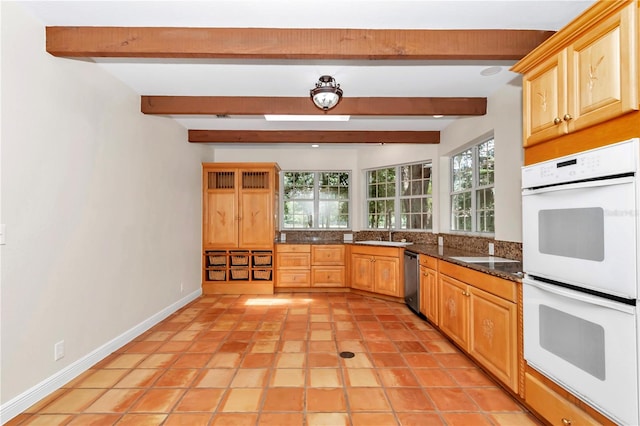 kitchen with light tile patterned flooring, sink, white double oven, and beam ceiling