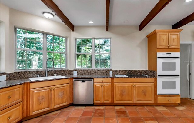 kitchen featuring light tile patterned flooring, dishwasher, beamed ceiling, sink, and white double oven