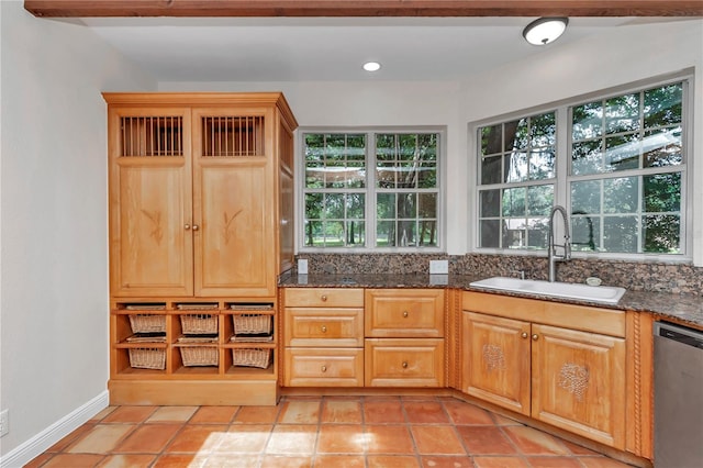 kitchen featuring light tile patterned floors, dishwasher, dark stone countertops, and sink