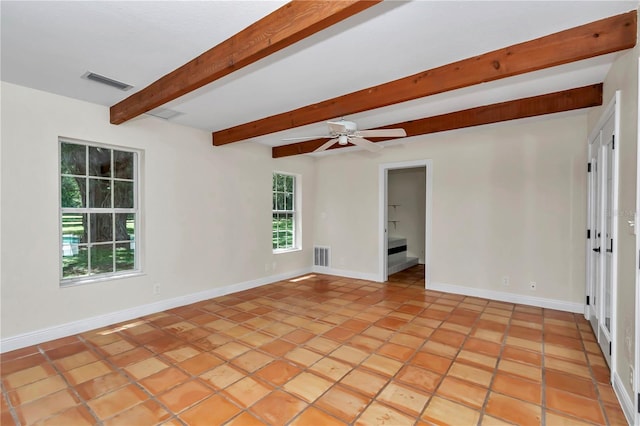 empty room with plenty of natural light, beamed ceiling, ceiling fan, and light tile patterned floors