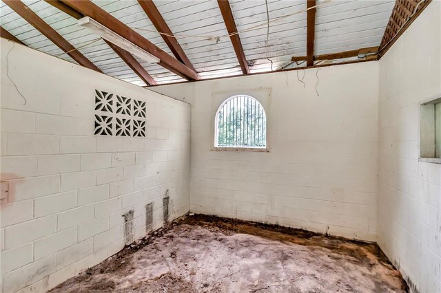 unfurnished room with vaulted ceiling with beams