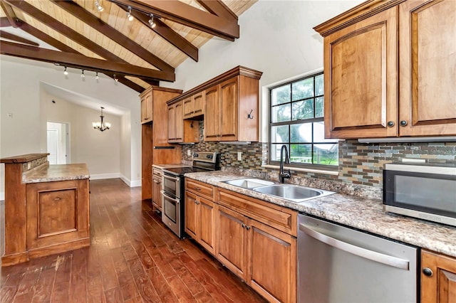 kitchen with vaulted ceiling with beams, track lighting, stainless steel appliances, sink, and backsplash