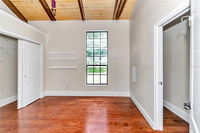 unfurnished bedroom featuring hardwood / wood-style floors, a closet, vaulted ceiling with beams, and wood ceiling