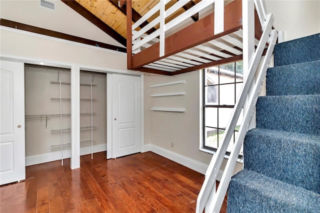 staircase with hardwood / wood-style flooring and high vaulted ceiling