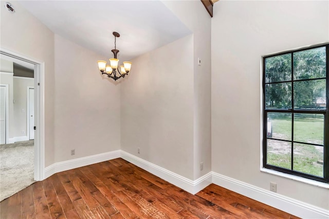 unfurnished room with dark carpet and a chandelier