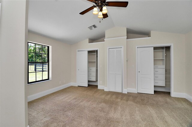 unfurnished bedroom with multiple closets, ceiling fan, lofted ceiling, and light colored carpet