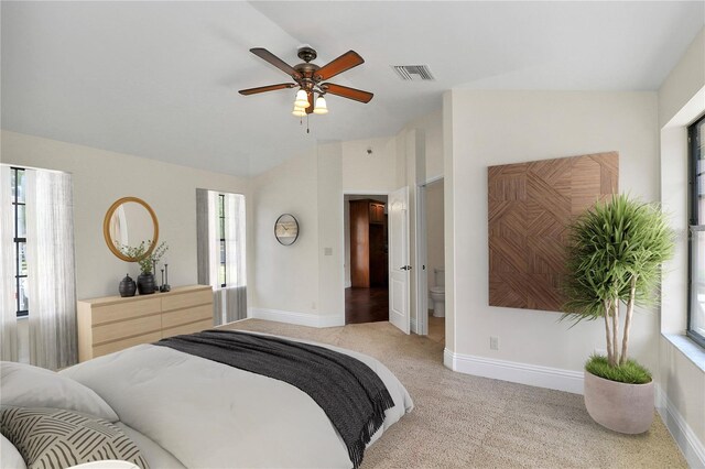 carpeted bedroom featuring vaulted ceiling, ensuite bath, and ceiling fan