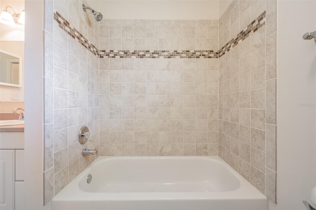 bathroom featuring tiled shower / bath combo and vanity