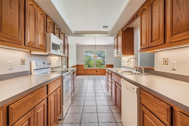 kitchen with pendant lighting, sink, light tile patterned floors, a tray ceiling, and white appliances