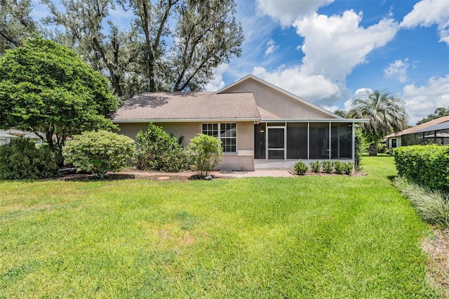 back of property with a sunroom and a lawn