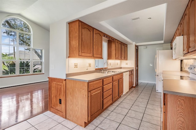 kitchen featuring lofted ceiling, sink, tasteful backsplash, light tile patterned floors, and white appliances