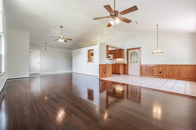 unfurnished living room featuring high vaulted ceiling, ceiling fan with notable chandelier, and light hardwood / wood-style floors