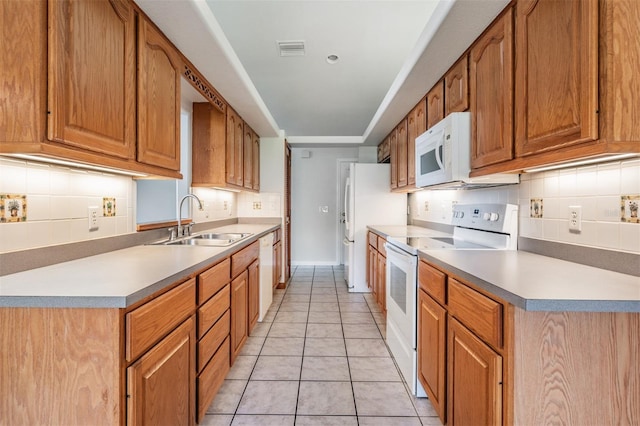 kitchen with light tile patterned flooring, white appliances, sink, and backsplash