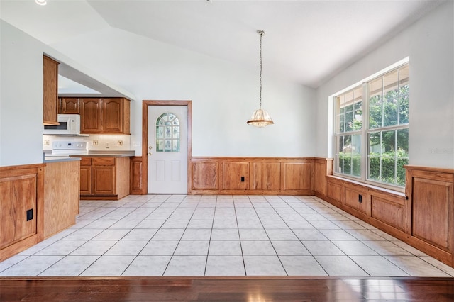 kitchen featuring hanging light fixtures, vaulted ceiling, light tile patterned floors, and white appliances