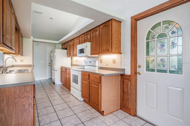 kitchen featuring sink, light tile patterned floors, white appliances, and decorative backsplash