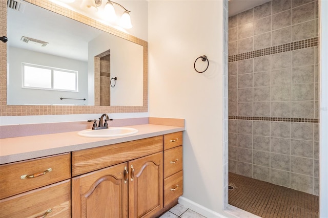 bathroom with tile patterned flooring, vanity, and tiled shower