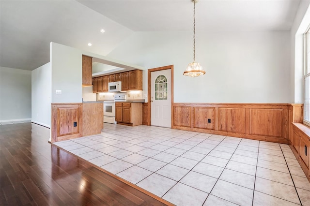 kitchen with pendant lighting, white appliances, lofted ceiling, and light wood-type flooring