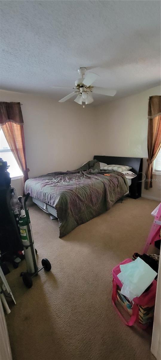 carpeted bedroom with a textured ceiling and ceiling fan