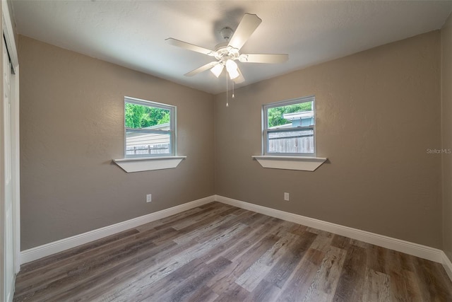 spare room with ceiling fan, a wealth of natural light, and wood-type flooring