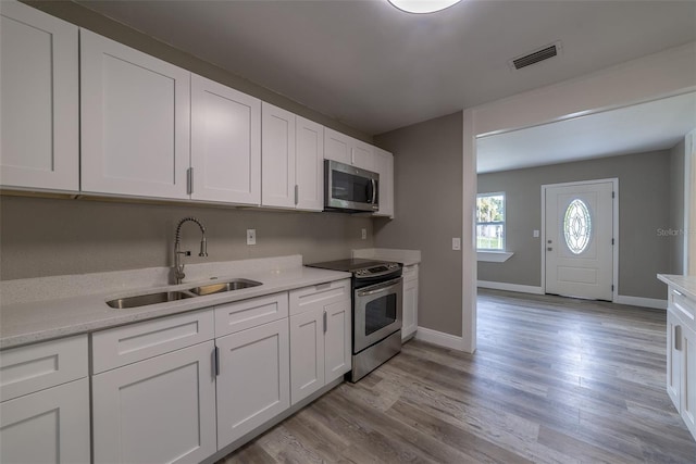 kitchen featuring stainless steel appliances, light hardwood / wood-style floors, sink, and white cabinets