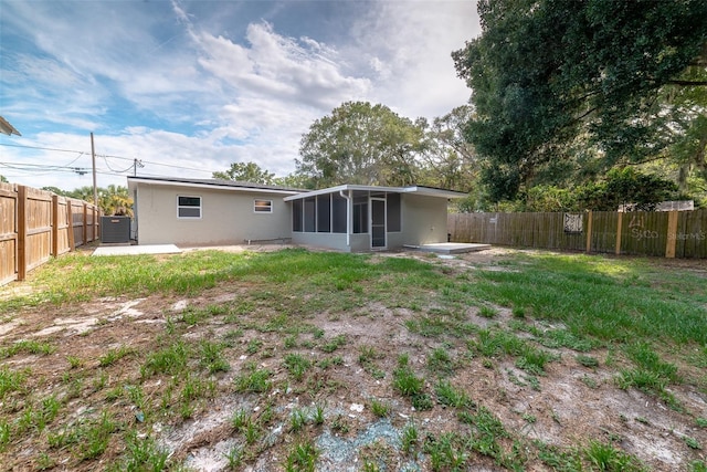 back of property with a sunroom, a patio area, and a lawn