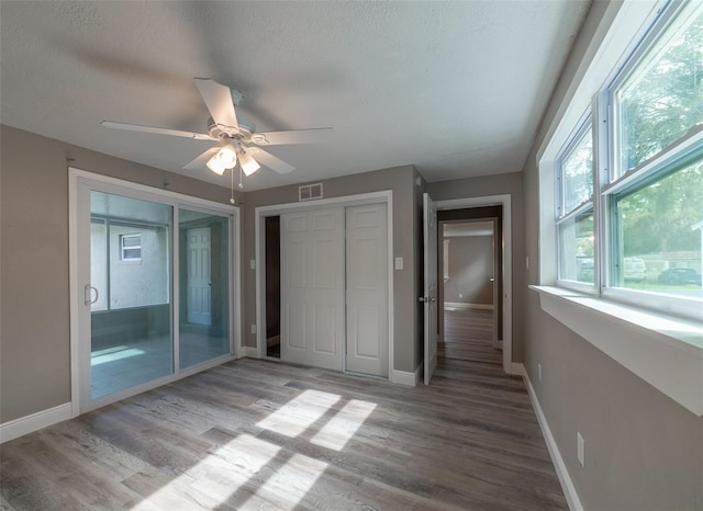 unfurnished bedroom with ceiling fan, hardwood / wood-style floors, a textured ceiling, and a closet